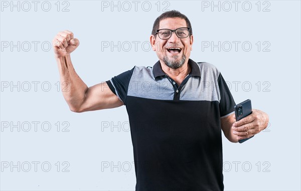 Happy winner senior man holding cell phone isolated. Senior person celebrating and holding phone isolated. Happy people holding smartphone and celebrating