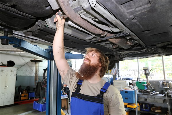 Symbolic image: Motor vehicle mechatronics technician inspects a car on the lift