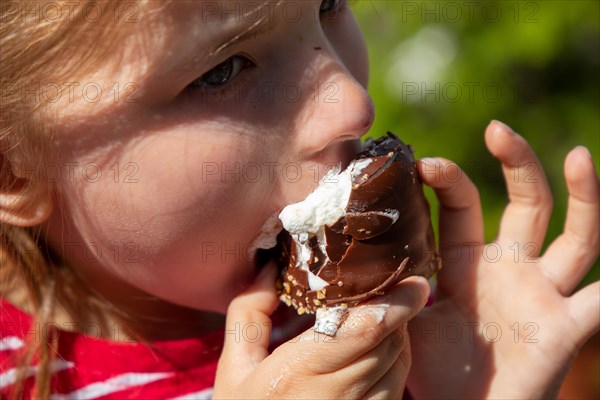 Seven-year-old girl eats a chocolate kiss at a folk festival