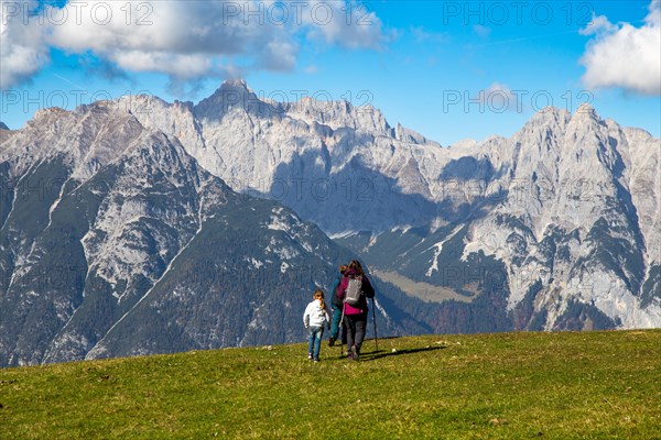 Hiking with children in Seefeld, Tyrol: Family hiking across an alpine meadow, with the Wetterstein mountains in the background