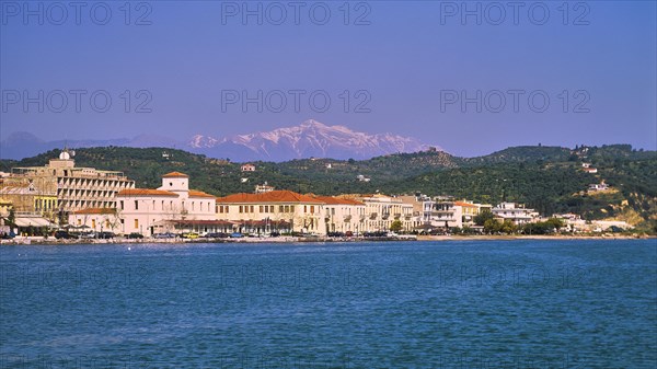 Coastal city view with buildings in front of a mountain backdrop under a clear blue sky, snow-covered Taygetos Mountains, Taygetos, Gythio, Mani, Peloponnese, Greece, Europe