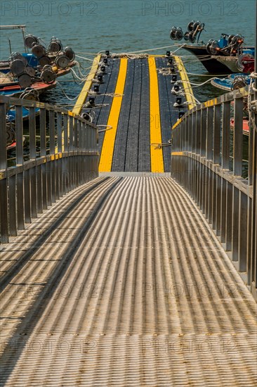 Metal gangplank to floating dock where numerous fishing boats are moored in South Korea