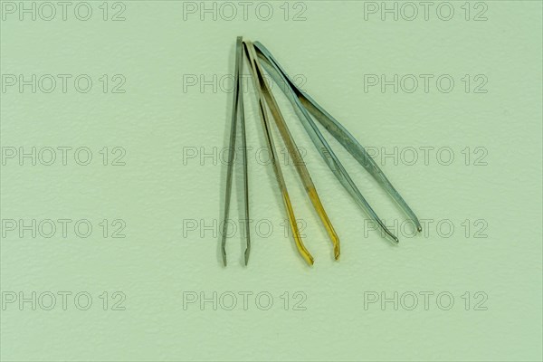 Three pair of tweezers side by side isolated on light textured background