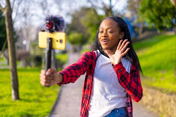 Streamer gesturing during an online video with mobile phone in the park of a city