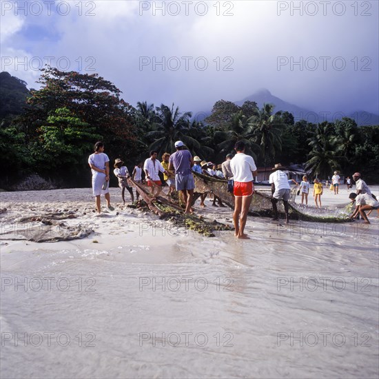 Seychelles, Mahe, Beau Vallon, fishermen pull fishing net ashore, Africa