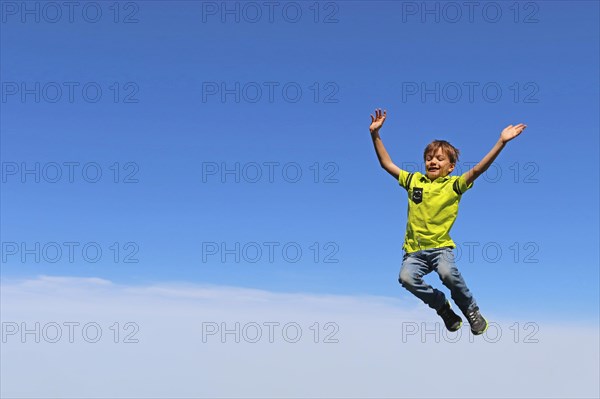 Symbolic image: Boy jumping into the air, blue sky in the background