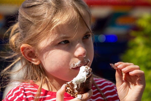 Seven-year-old girl eats a chocolate kiss at a folk festival