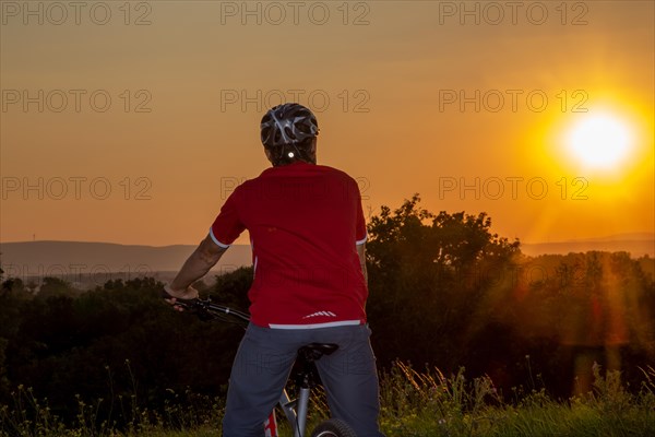 Symbolic image: Mountain biker enjoying the view at sunset