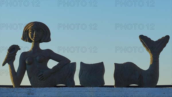 Sculpture of a reclining woman against the blue morning sky, mermaid, Gythio, Mani, Peloponnese, Greece, Europe