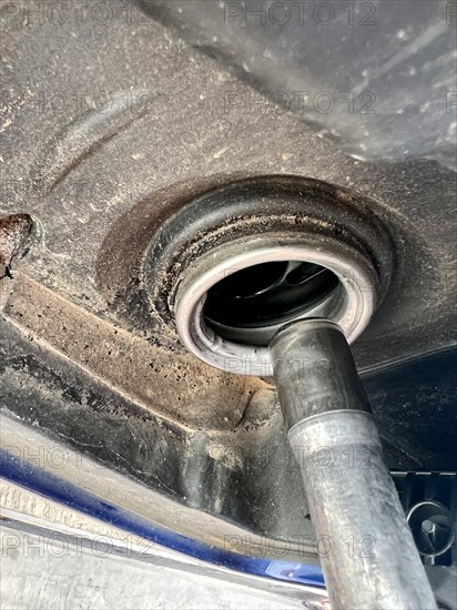 Detail of a person's hand pouring gas into a car at a gas station. refueling the car's tank