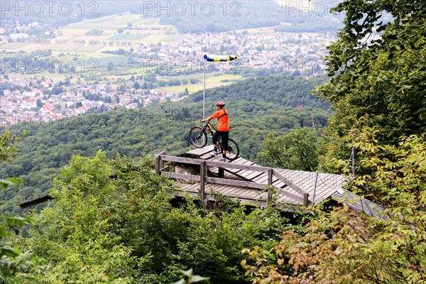 Mountain biker stands on the launch ramp for hang-gliders below the Melibokus and looks out over the Rhine plain