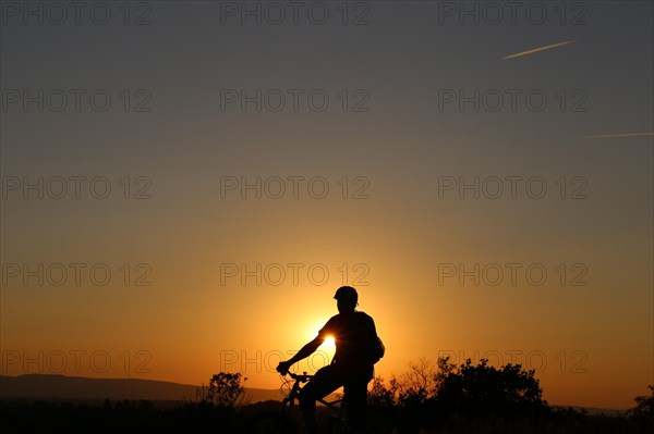 Symbolic image: Silhouette of a mountain biker on a warm summer evening