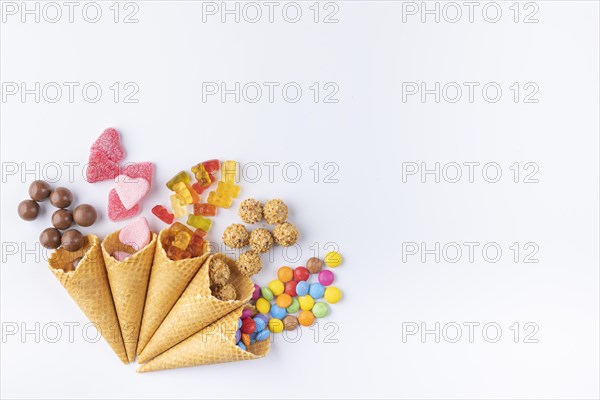 Various sweets in and out of ice-cream cones on a white background, copy room