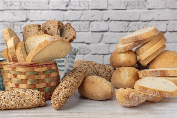 An assortment of bread and pastries in a beautiful basket on a wooden counter
