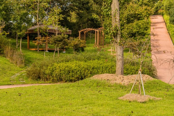 Landscape of urban park with covered gazebo, wooden trellises and concrete hiking trail in South Korea