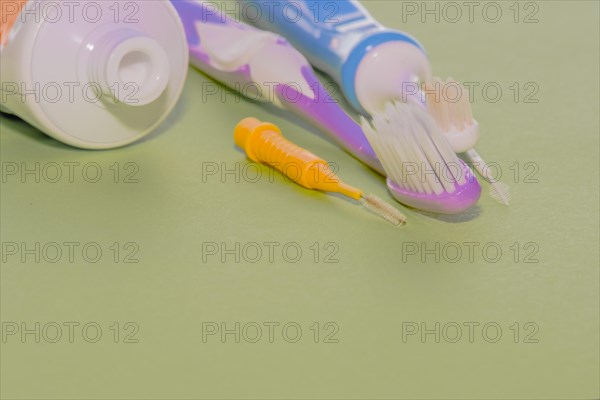Closeup of toothbrushes and flossing picks next to opened tube of toothpaste