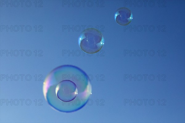 Soap bubbles four coloured film of soapy water on top of each other in front of a blue sky