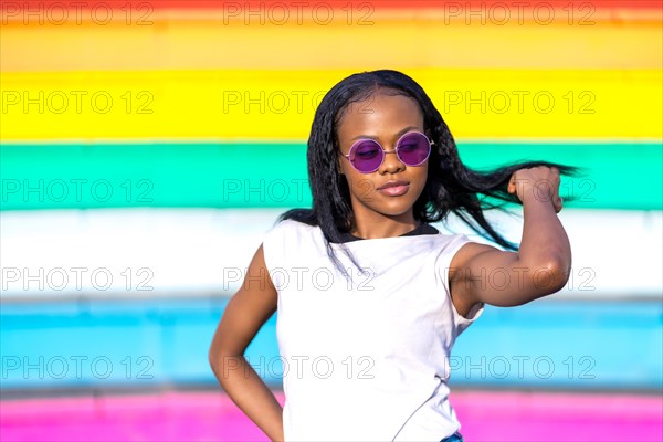 Frontal portrait of a cool african woman in sunglasses posing next to a striped colorful stairs