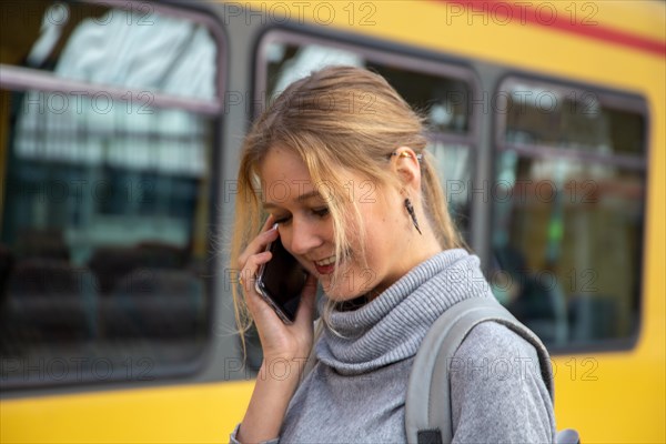 Close-up of a young woman in front of a train at the station