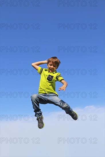 Symbolic image: Boy jumping into the air, blue sky in the background