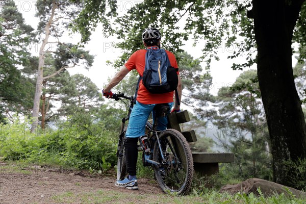 Mountain biker taking a break on a bench in the Palatinate Forest near the Weinbiet above Neustadt an der Weinstrasse