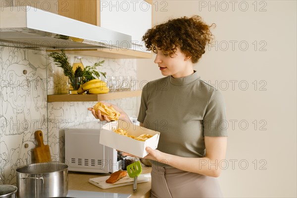 Young woman holding pappardelle pasta in hands over the pot with boiling water