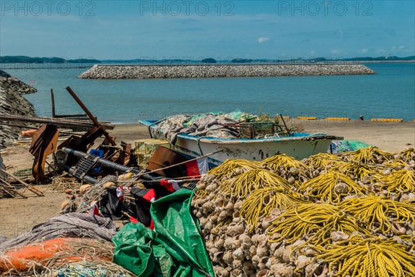 Small fishing boat filled with nets and gear beached among assortment of fishing paraphernalia in Yeosu, South Korea, Asia