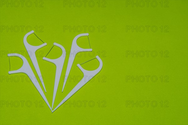 Closeup of white of plastic flossing picks on green background