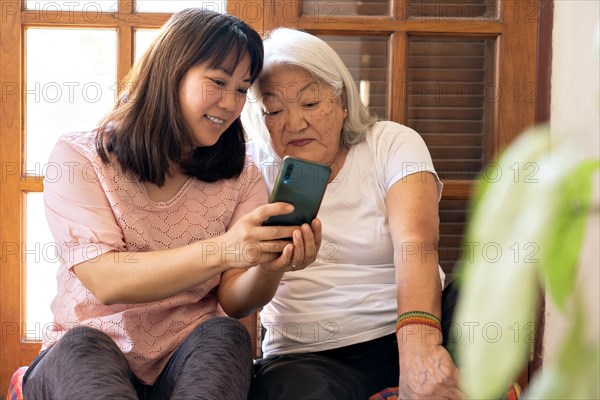 Japanese adult daughter shares photos taken with her smartphone with her elderly mother