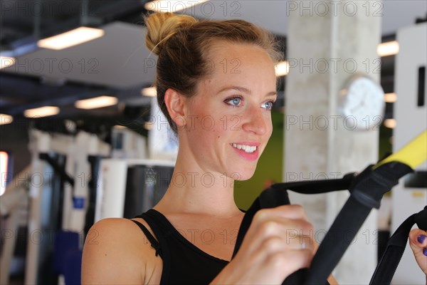 Young woman doing TRX training in the gym, (Neuhofen, Rhineland-Palatinate)