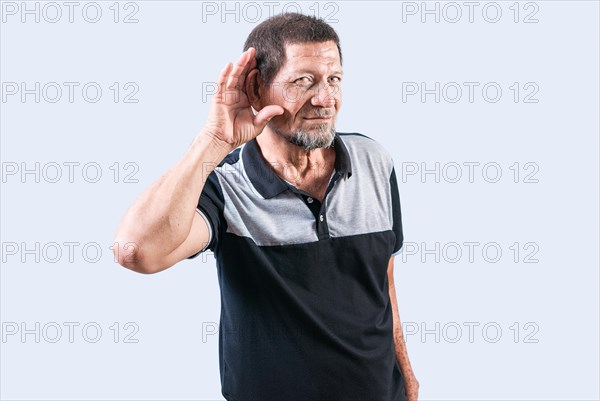 Senior man with hand on ear hearing a rumor isolated. Old man listening to a rumor isolated