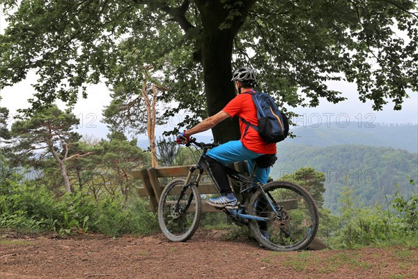 Mountain biker taking a break on a bench in the Palatinate Forest near the Weinbiet above Neustadt an der Weinstrasse