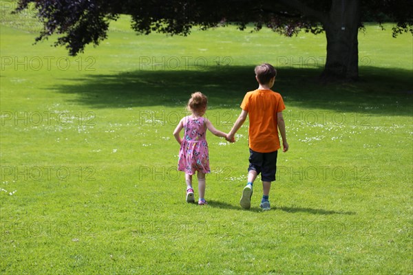 Boy and girl (siblings) running in a meadow