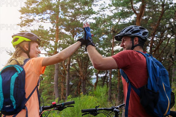 Happy young couple mountain biking in the forest