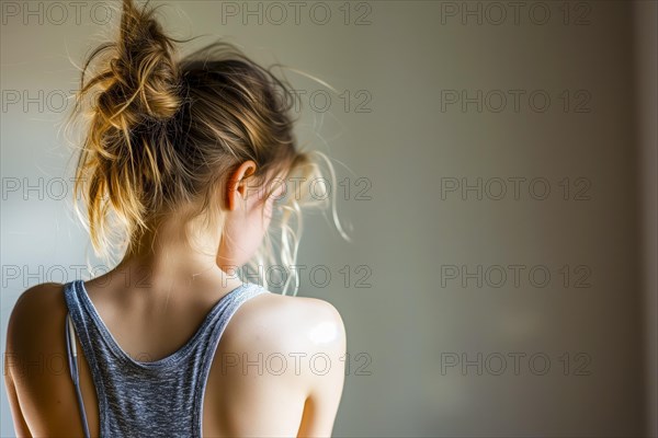 Back view of a girl in soft light, her hair tied into a loose bun, symbolising depression and abuse, AI generated, AI generated