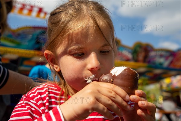 Seven-year-old girl eats a chocolate kiss at a folk festival