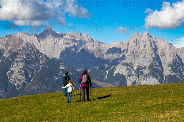 Hiking with children in Seefeld, Tyrol: Family hiking across an alpine meadow, with the Wetterstein mountains in the background