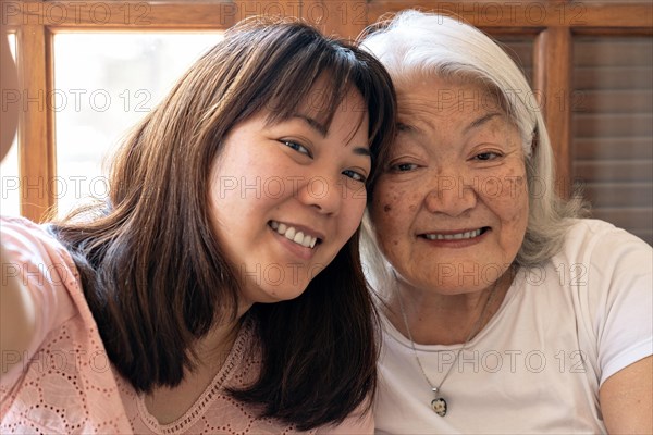 Portrait of mother and daughter. Japanese elderly woman with white hair and daughter smiling taking a selfie