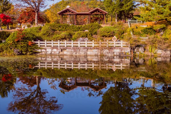 Reflections of covered picnic tables on hill next to small man made pond in South Korea