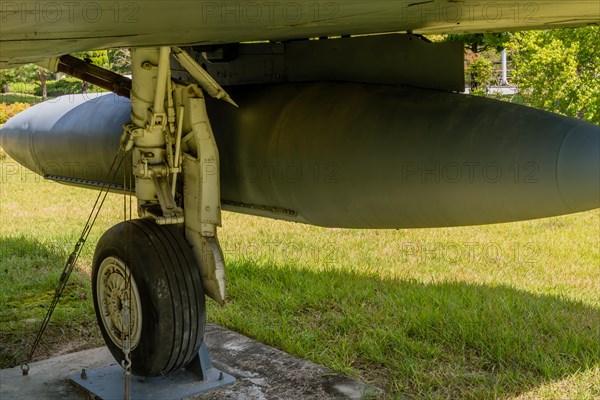 Closeup of starboard landing gear and external fuel tank on military fighter jet on display in public park