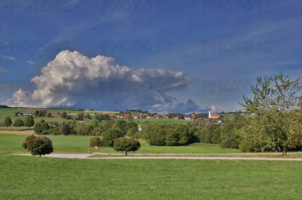 Threatening thundercloud over a sunny, hilly landscape with a village in the foothills of the Alps, Kirchdorf near Haag, Upper Bavaria, Bavaria, Germany, Europe