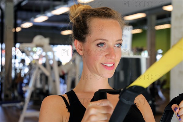 Young woman doing TRX training in the gym, (Neuhofen, Rhineland-Palatinate)