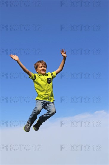 Symbolic image: Boy jumping into the air, blue sky in the background