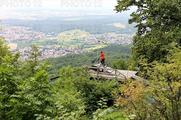Mountain biker stands on the launch ramp for hang-gliders below the Melibokus and looks out over the Rhine plain