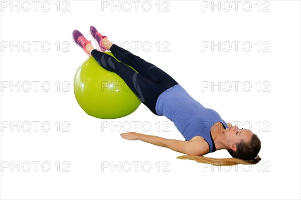 Symbolic image: Young woman doing exercises on an exercise ball against a white background