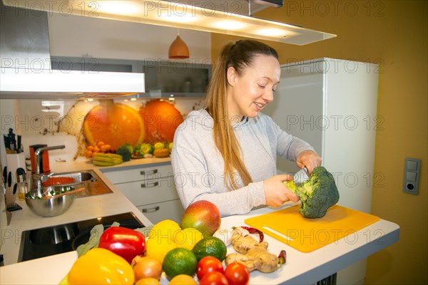 Vegan cooking: Young woman cuts broccoli