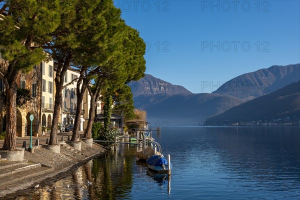 Old Beautiful Town with Building and Trees on the Waterfront on Lake Lugano with Boat in a Sunny Day with Mountain in Morcote, Ticino, Switzerland, Europe
