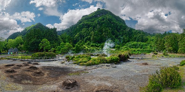 Panoramic view of a geothermal area with steam, surrounded by a forest under a dynamic sky, Fumarolas Lagoa das Furnas, Furnas, Sao Miguel, Azores, Portugal, Europe
