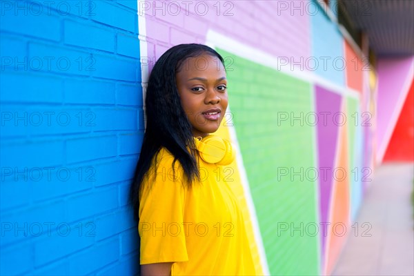 Portrait with copy space of a cool african woman leaning on a colorful wall and looking at camera