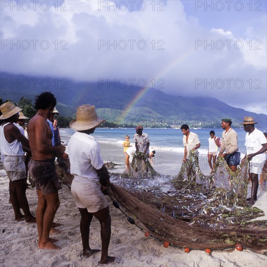 Seychelles, Mahe, Beau Vallon, fishermen pull fishing net ashore, Africa